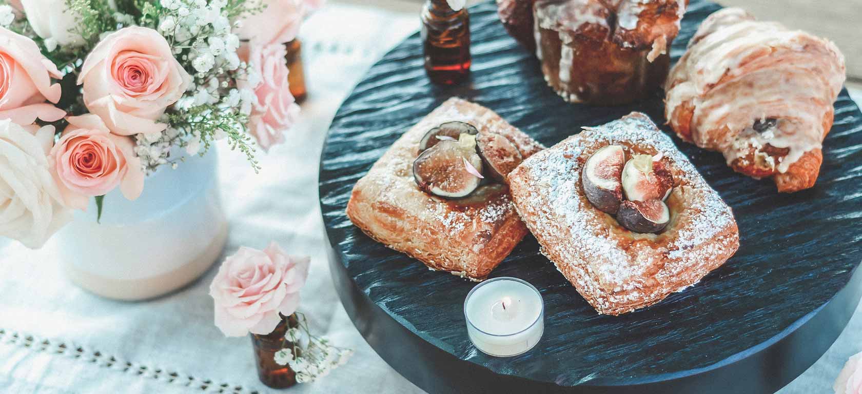 Tender pink flakey pastry next to pink roses.