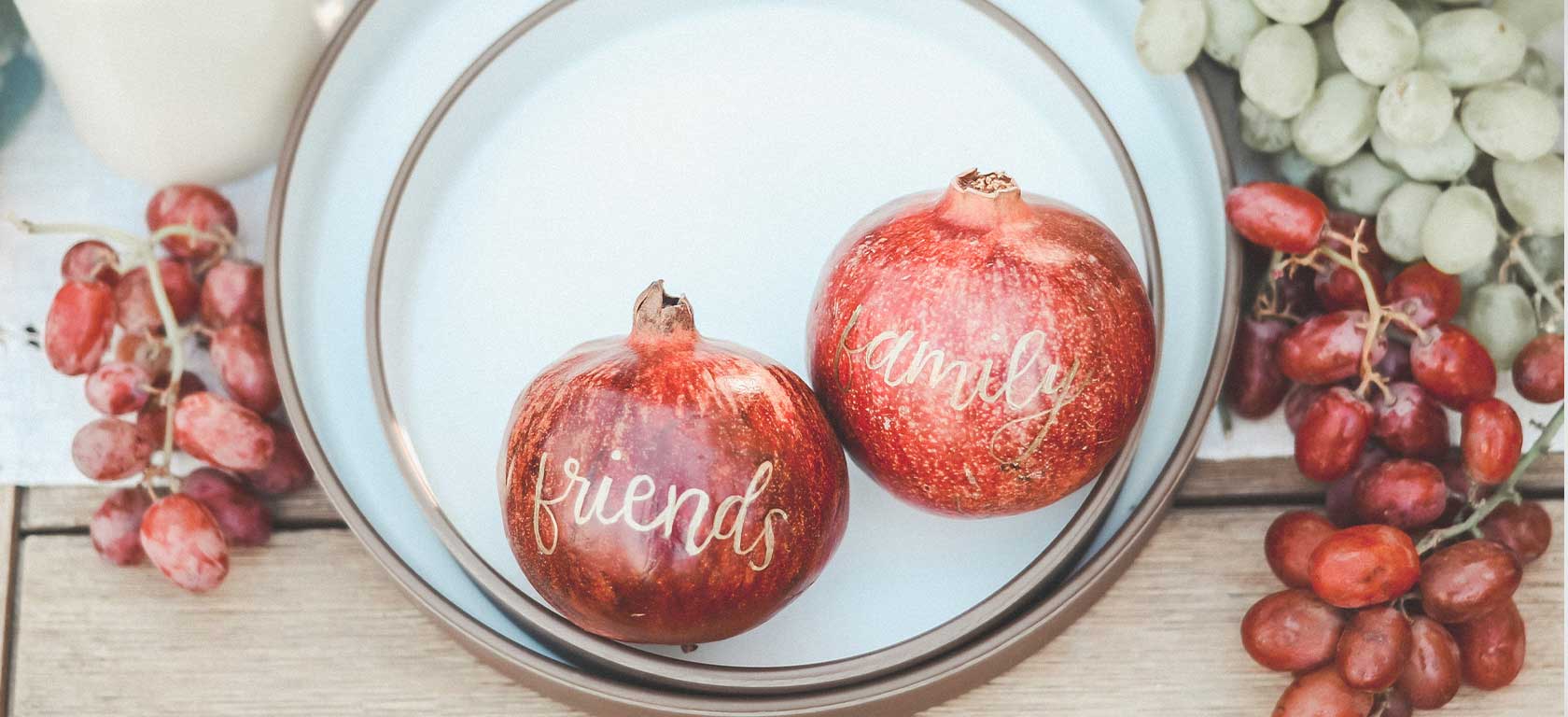 Elegant gold-trimmed plate holding tender pomegranates with the words friends and family on them.