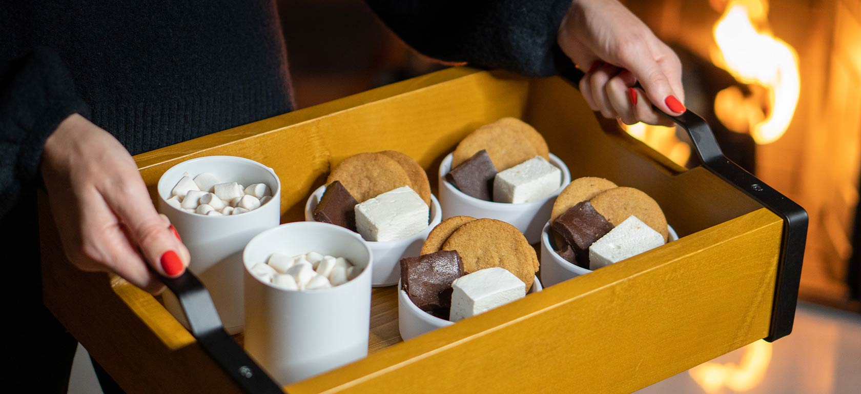 Minimalist golden brown wooden tray holding array of elegant mugs filled with smores.