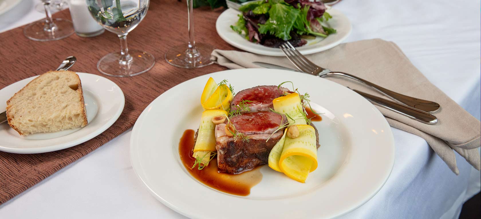Beautifully plated rare steak on elegant white ceramic plate.