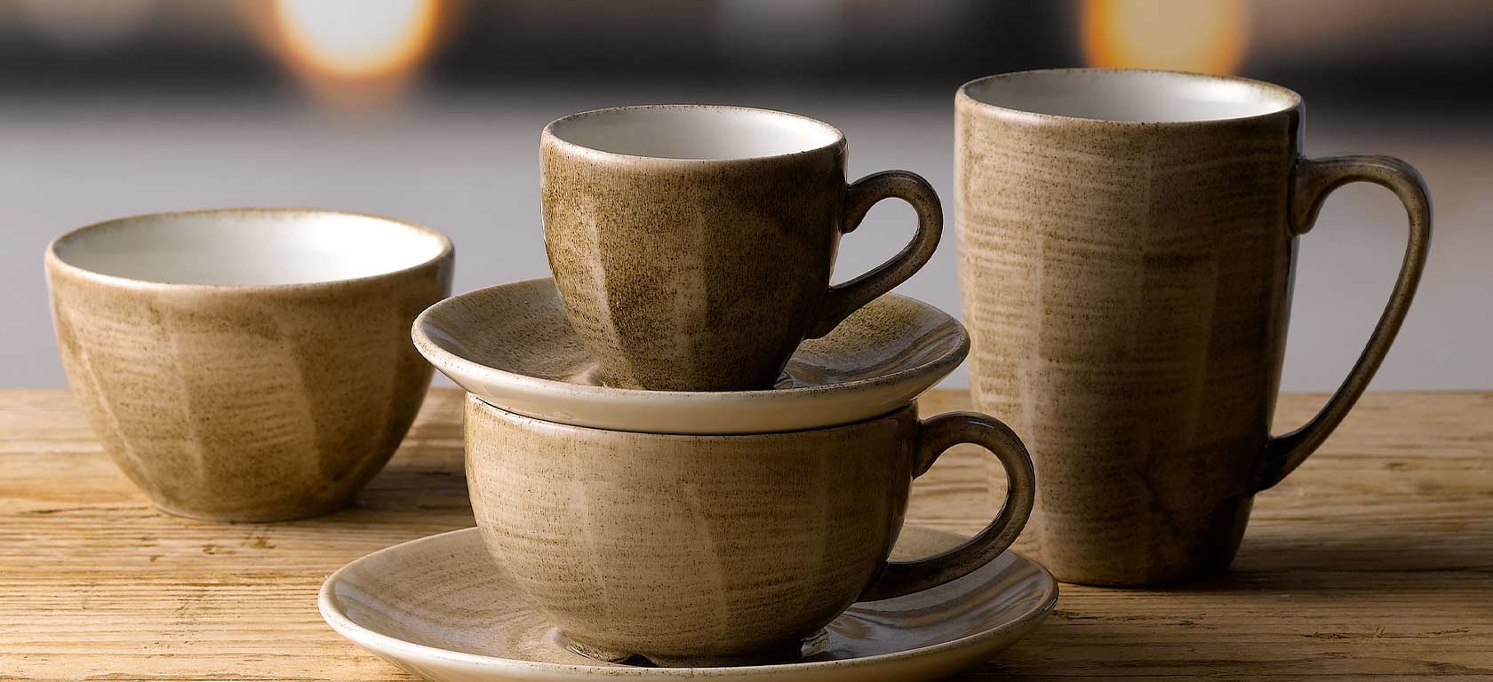 Rustic earth-toned saucers and mugs with angular features.