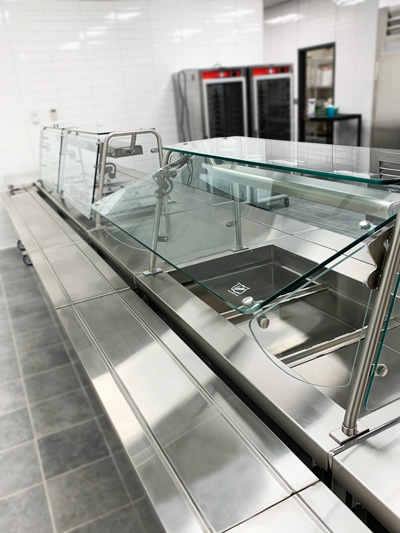 Vertical shot of glass cover on a stainless steel food display for a cafeteria.
