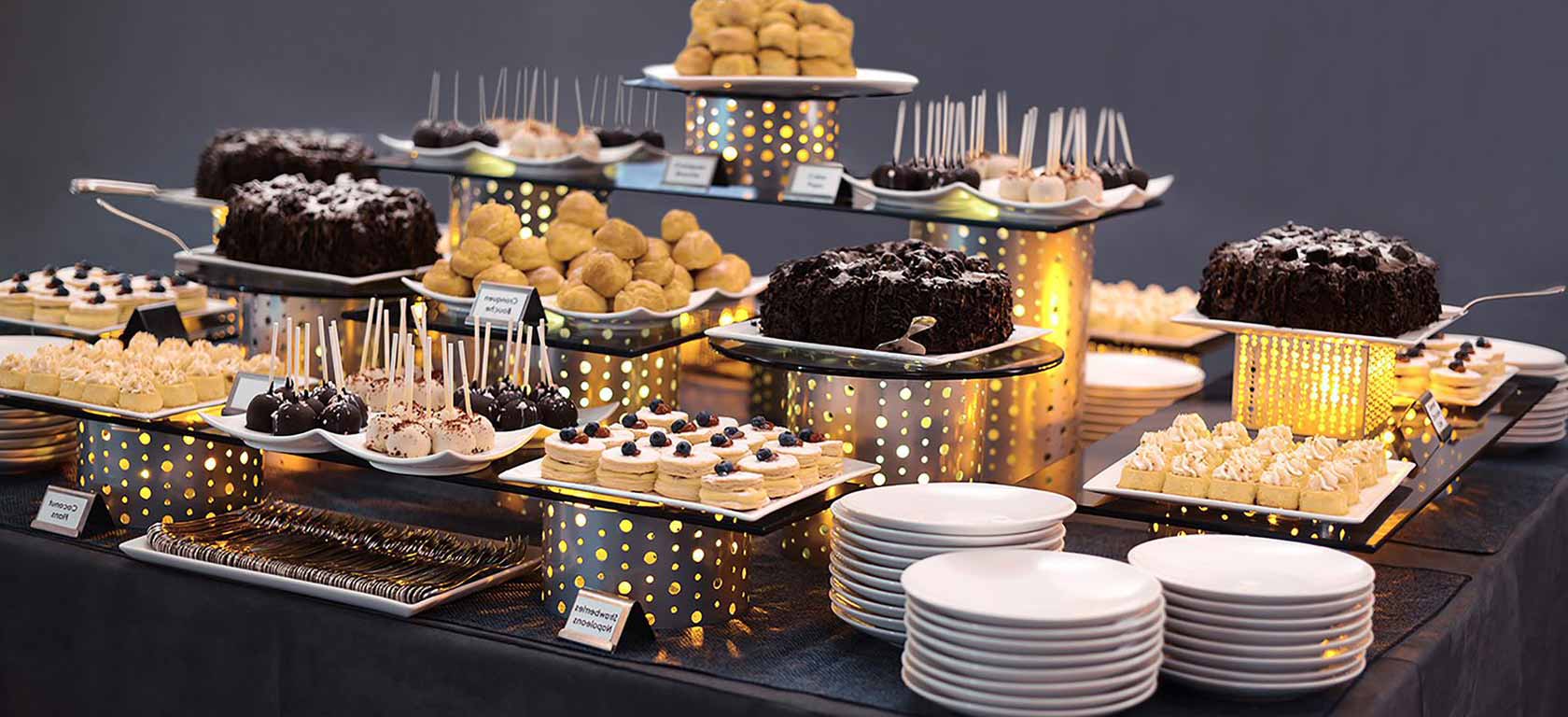 Buffet array of deserts on chrome utensils and risers.