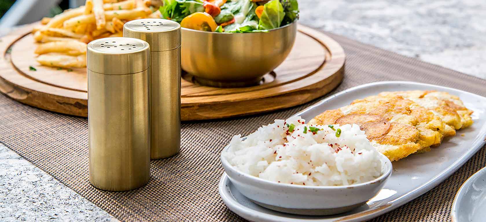 White round ceramic tableware on table accompanied by golden salt and pepper shakers