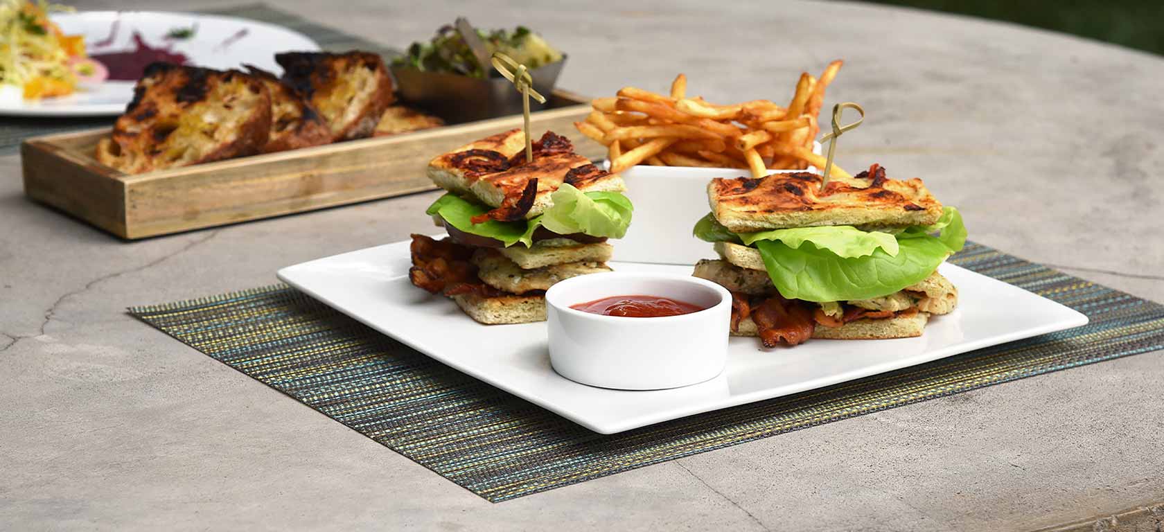 Sandwich and fries arranged on simplistic white ceramic plates.