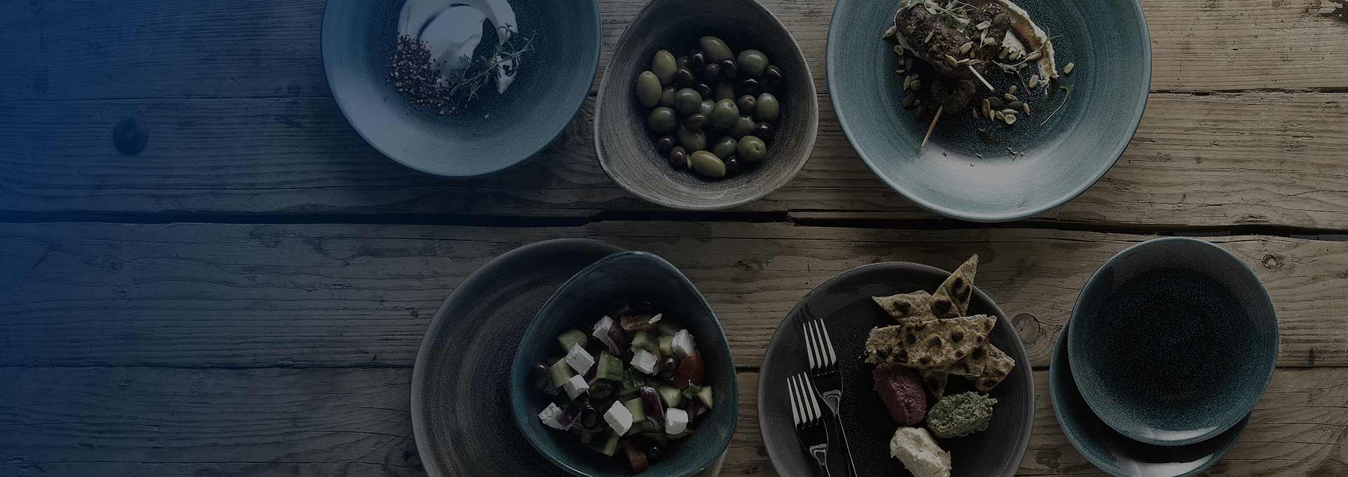 blue gradient over tabletop with fresh greens served on elegant dish-ware.