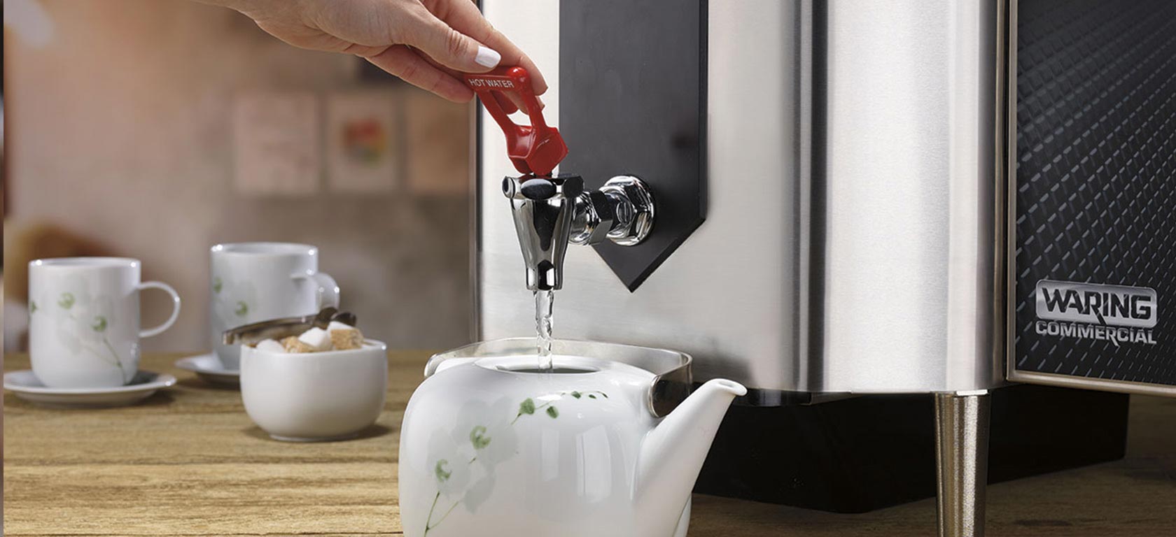 Chrome-finished Waring coffee maker pours hot water into a ceramic teapot.