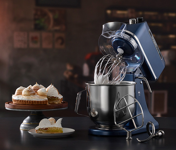 Waring Commercial blue-tinged chrome finish electric mixer surrounded by an assortment of baked goods.